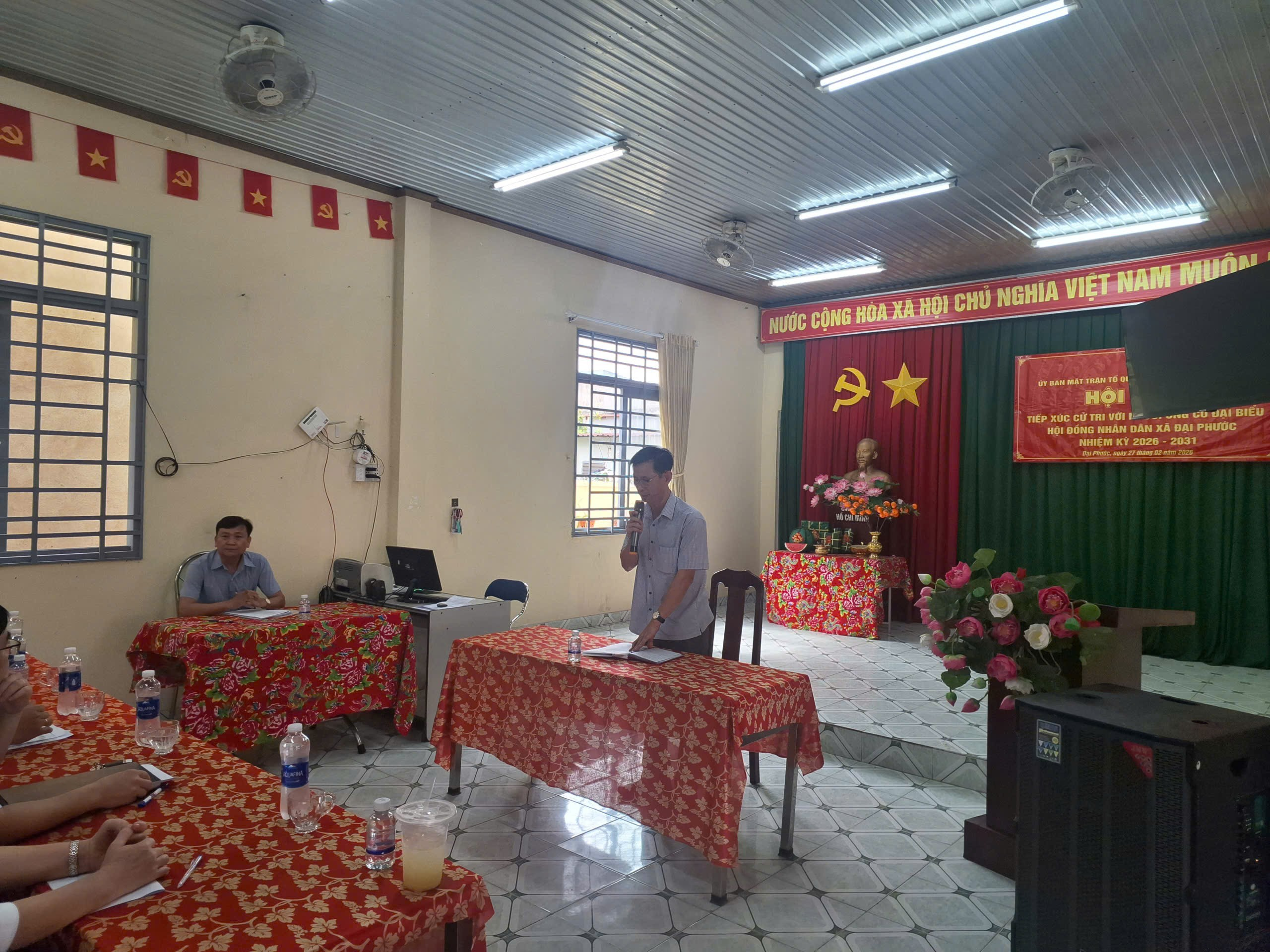 'A group of people sitting at tables in a room with red and green flags

Description automatically generated'